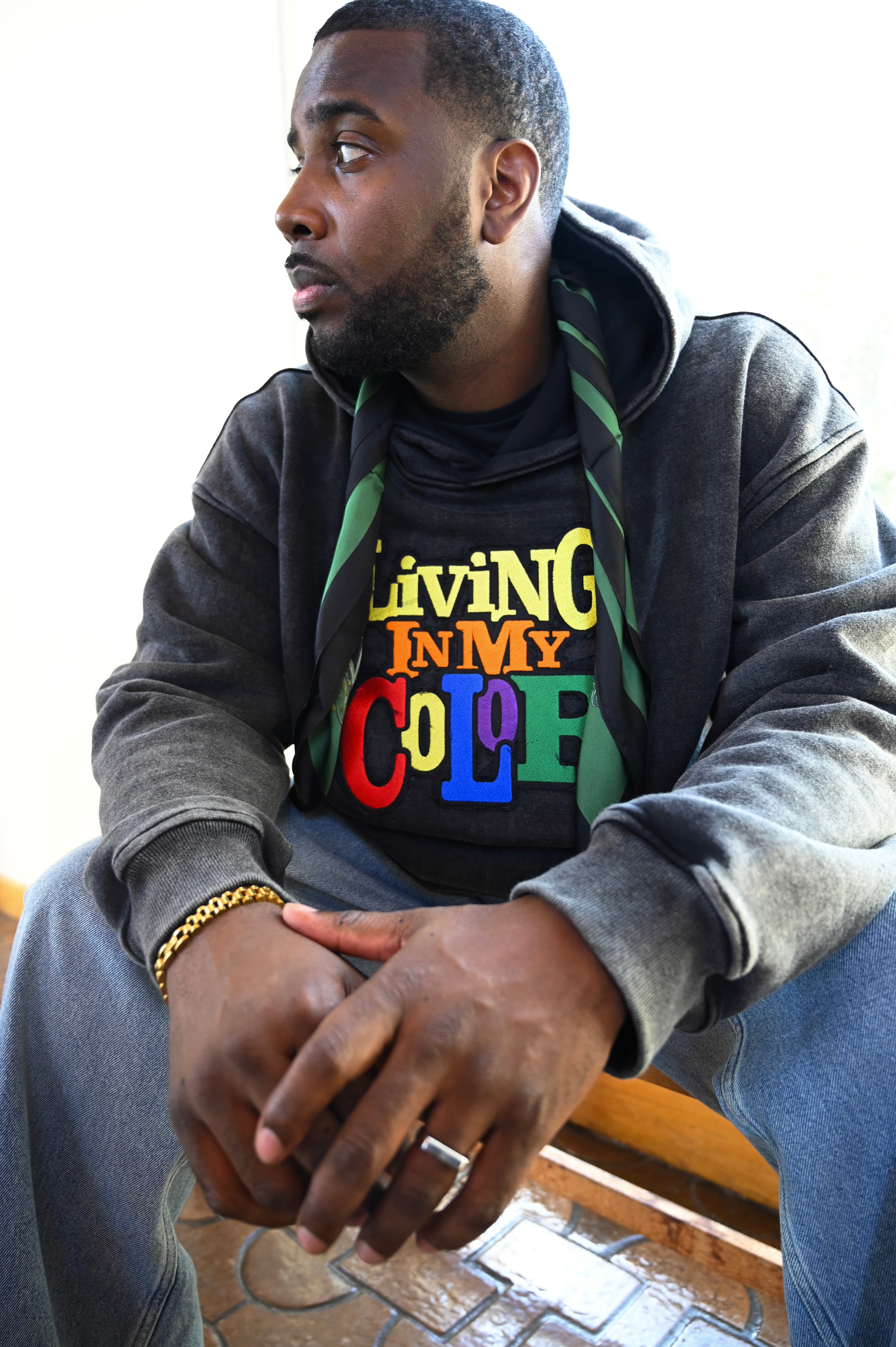 Man wearing a hoodie with text sitting on a bench.