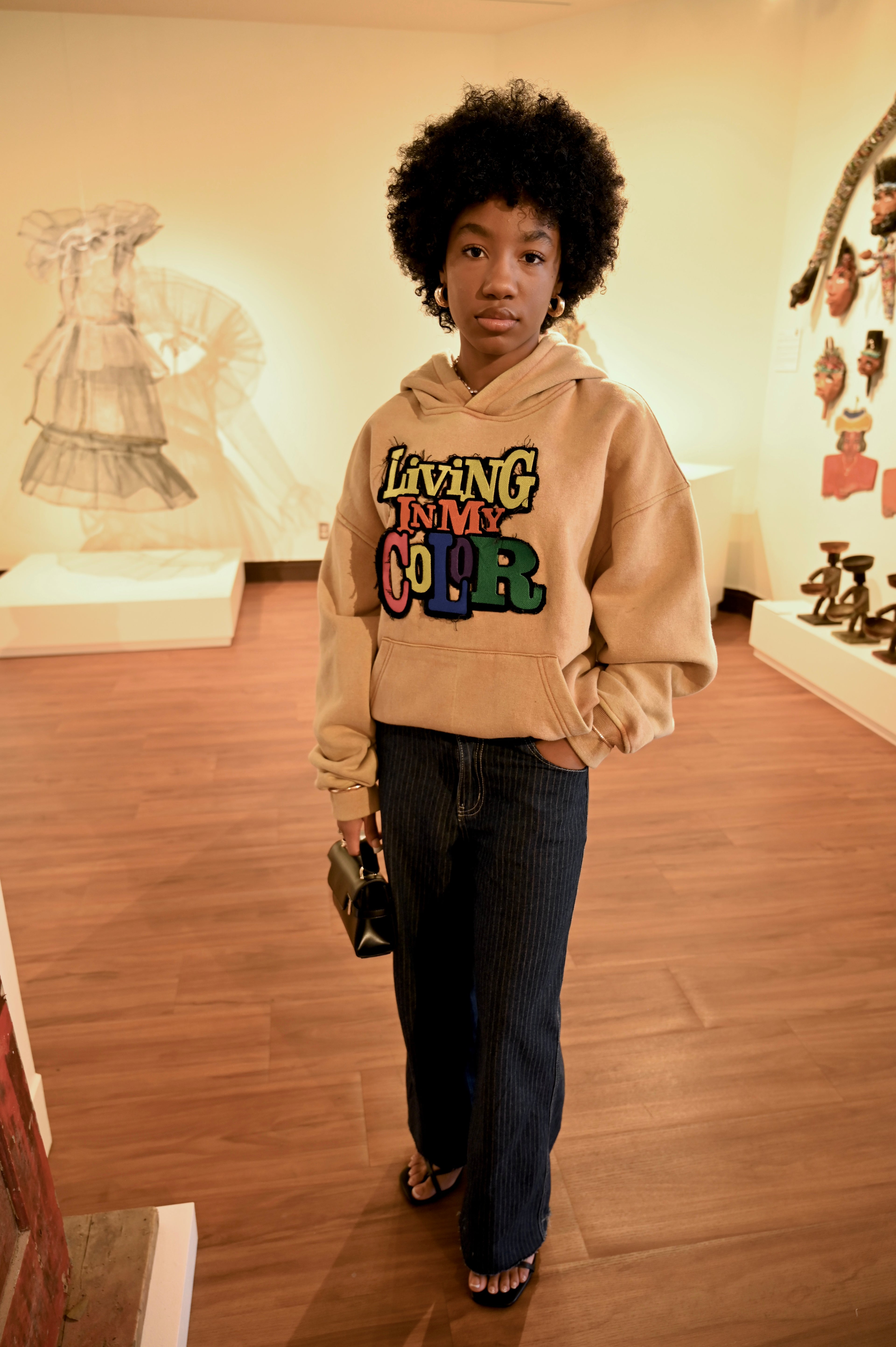 Person wearing a beige hoodie with colorful text in an indoor setting