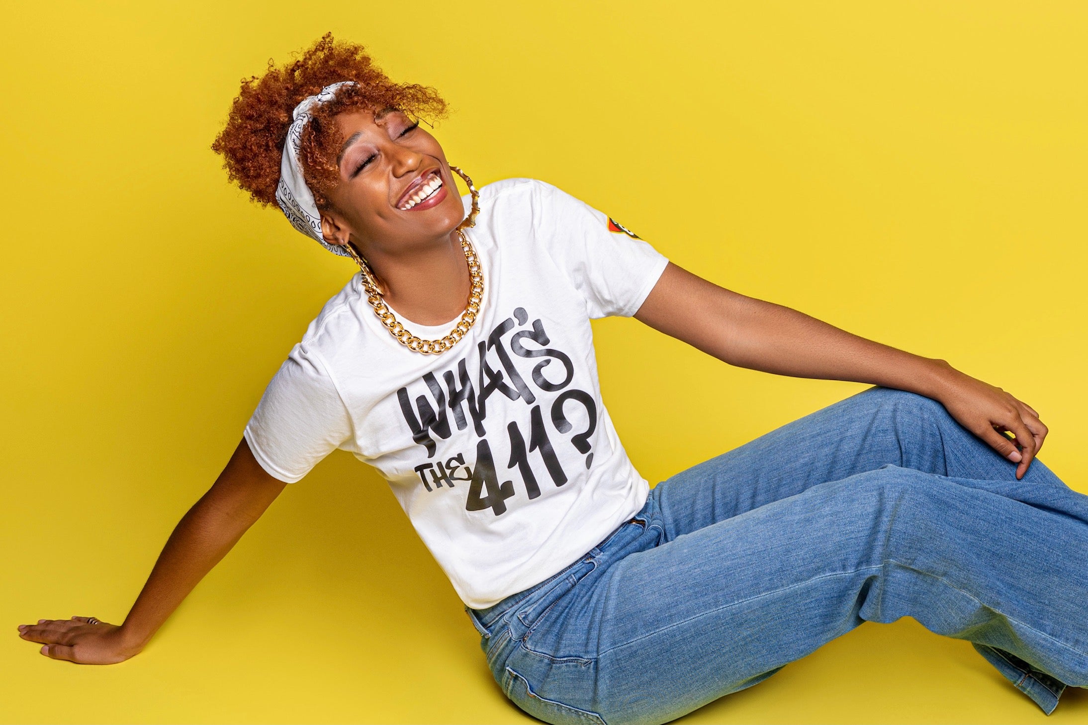 Black female wearing "what's the 411?" shirt by Vintage '88. Embracing black culture from the 90s. Rocking vintage 90s outfit. 90s style shirts and accessories. Where to shop 90s clothing. 90s jackets and gear. 